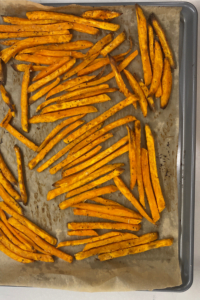 Baked sweet potato fries fresh from the oven on a sheet pan.