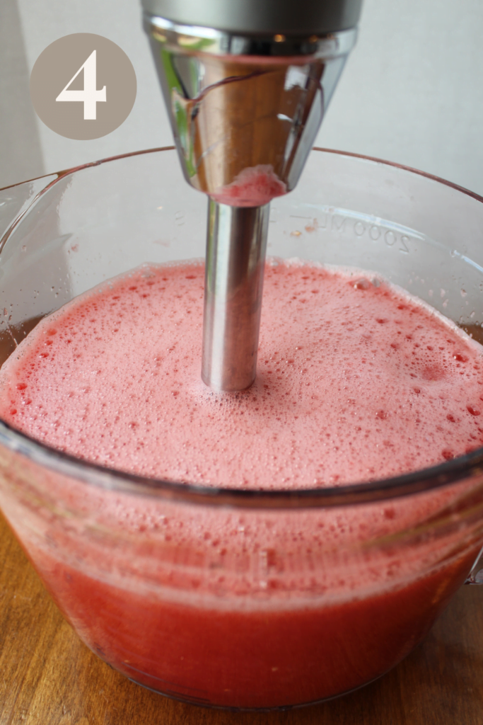 Blending watermelon with a immersion blender in a bowl.
