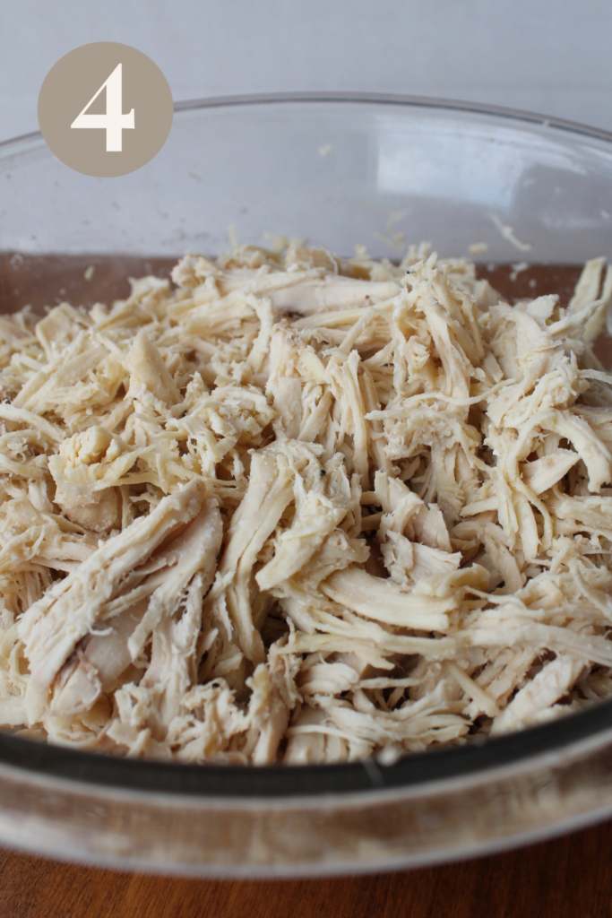 Finished shredded chicken placed in a glass bowl.