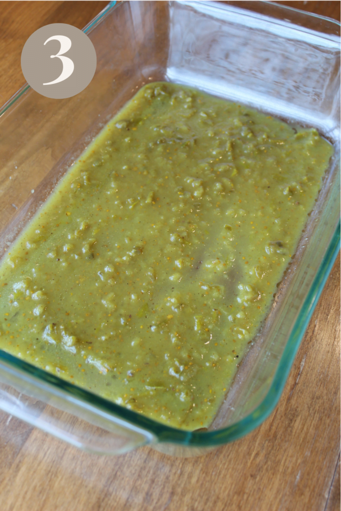 Green enchilada sauce poured on the bottom of a pan.