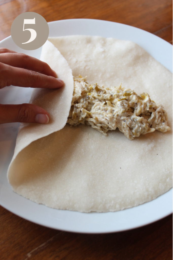 The tortilla placed on a plate and the left side folded in.