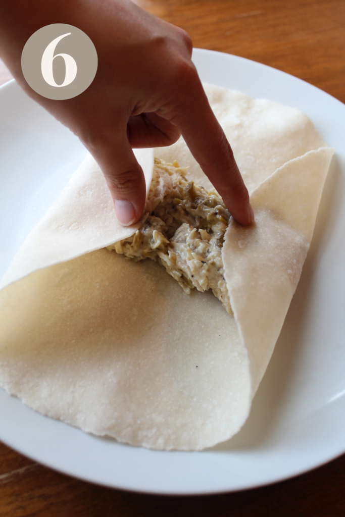 The tortilla on a plate with the left and right side folded in.