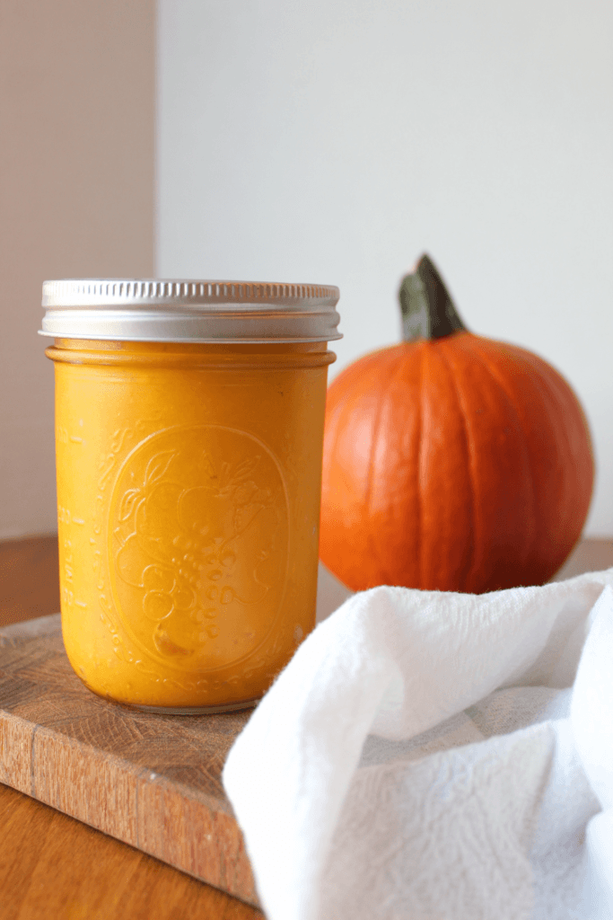 Pumpkin Puree in a jar next to a pumpkin.
