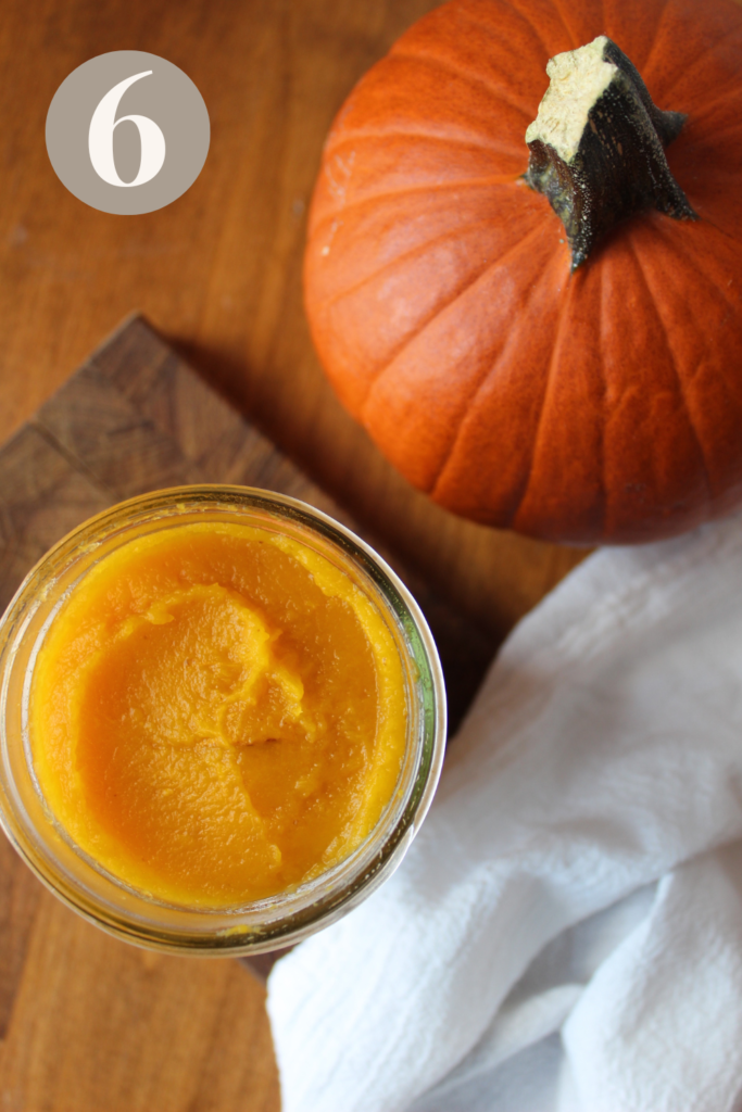 Pumpkin puree on the counter next to a orange pumpkin.