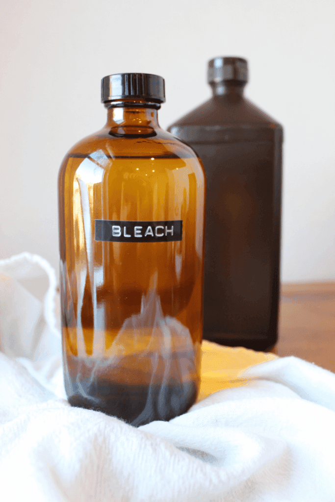 A towel, bleach and hydrogen peroxide sitting on a table.