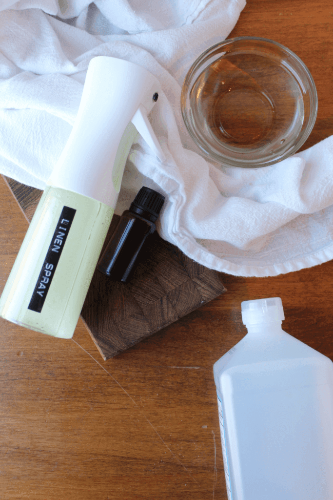 Linen spray, water, witch hazel, essential oils and towel on a table.
