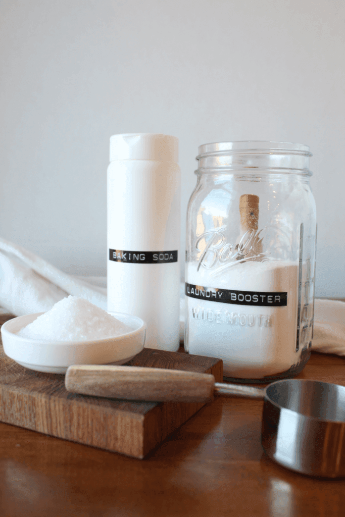 Scent Booster, baking soda and Epsom Salt sitting on a table.