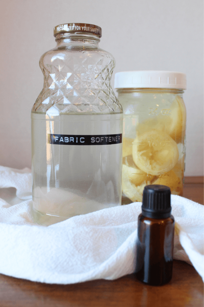 Fabric softener, essential oil and lemon vinegar sitting on a table.