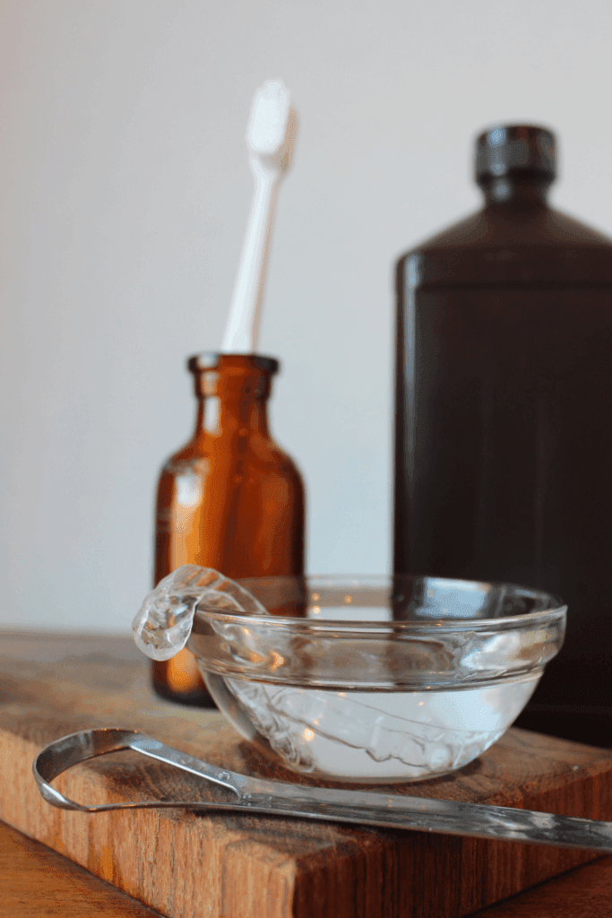 Oral tools and appliances sitting on a counter with water and hydrogen peroxide cleaner.