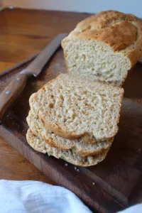 Gluten free bread sliced on a wood cutting board with a knife to the side.