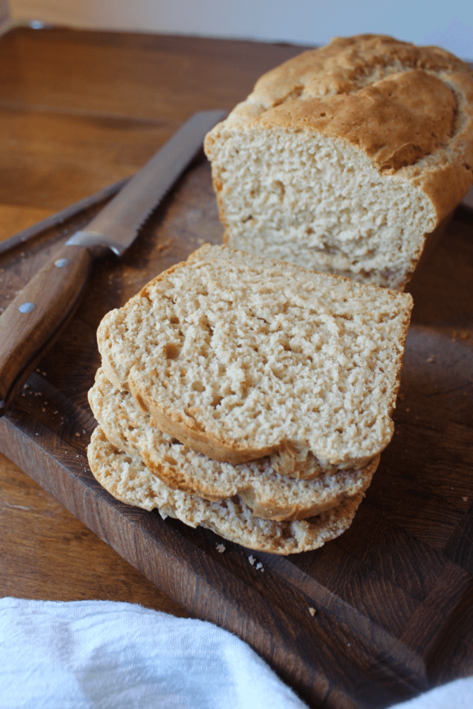 Gluten free bread sliced on a wood cutting board with a knife to the side.