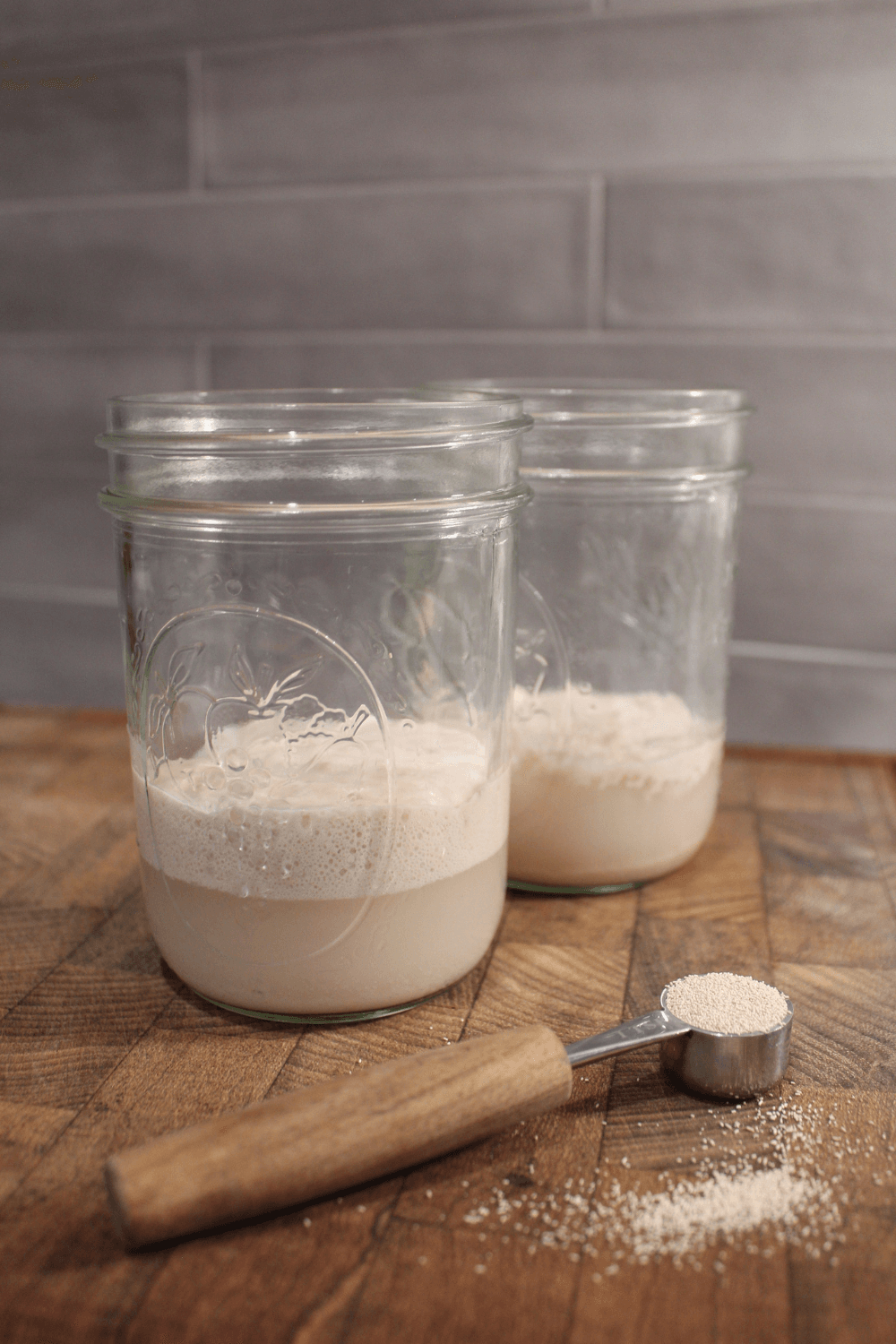Proofing yeast in mason jars with active yeast on a counter.