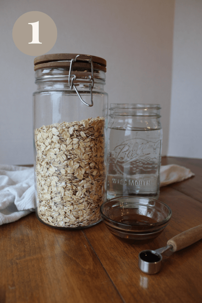 Oat milk ingredients on a table; oats, water, maple syrup, and vanilla.