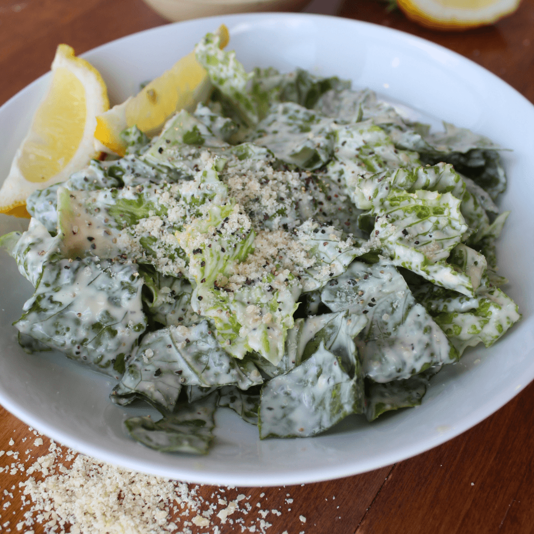 Caesar salad in a bowl with lemon wedges.
