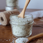 Rosemary salt in a mason jar with a wooden mini spoon sticking out of it.