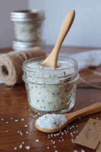 Rosemary salt in a mason jar with a wooden mini spoon sticking out of it.
