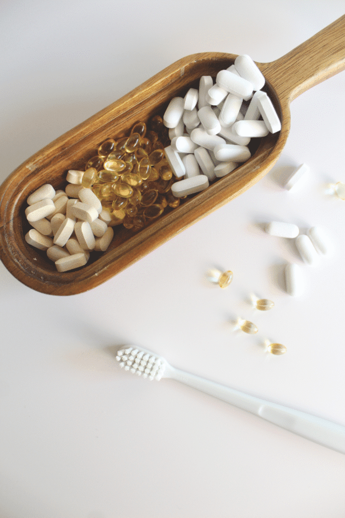 Vitamins pilled in a wood dish next too a white toothbrush.