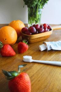 A table of fruit with a toothbrush and toothpaste in the center.