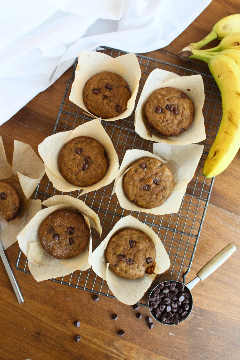 Banana bread muffins on a wire rack on a wood table.