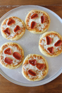A metal sheet pan of mini frozen pizzas.