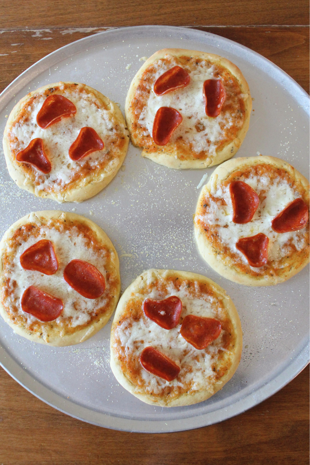 A metal sheet pan of mini frozen pizzas.