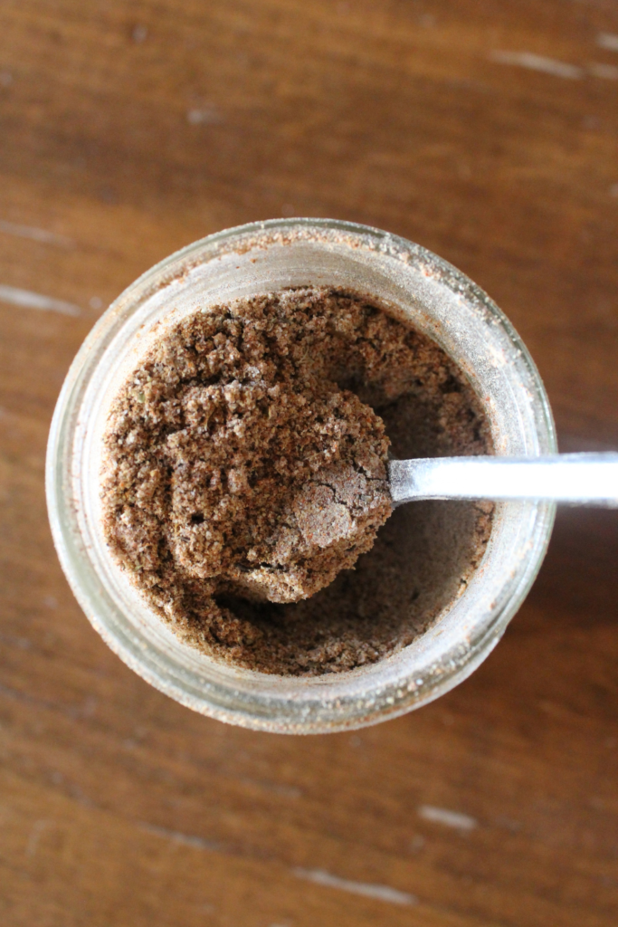 Taco seasoning in a jar with a spoon scooping it out.